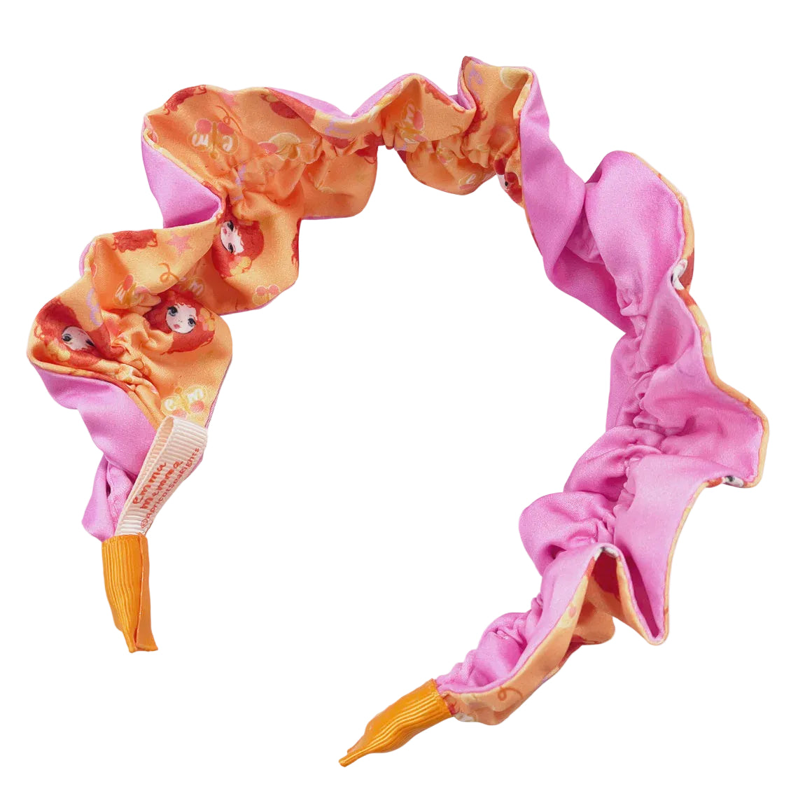 A reversible Emma Memma headband with one side pink and the other side orange, featuring a pattern with Emma Memma cartoon characters.