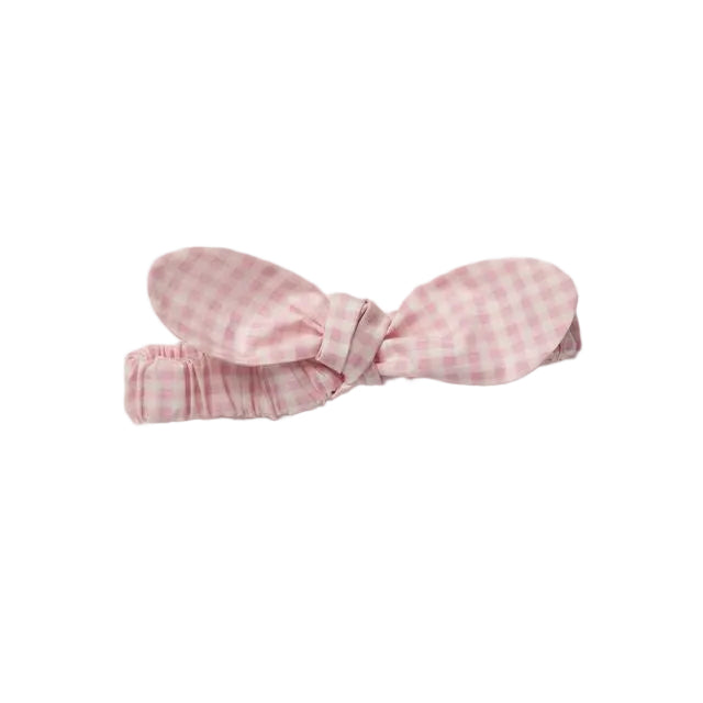 A small fabric hair bow in a light pink and white gingham check pattern, photographed on a clean, light gray background.