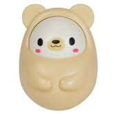A cute, rounded bear-shaped container or toy in a pale cream color, featuring a stylized face with black eyes, a yellow snout, and pink cheeks, set against a plain white background.