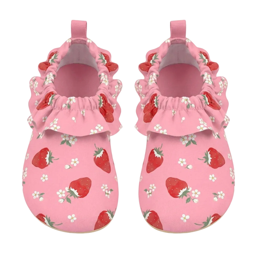 A pair of pink baby mule style swim shoes with a strawberry and white flower print, featuring ruffled trim around the open back and pull tabs, shown on a light gray background.