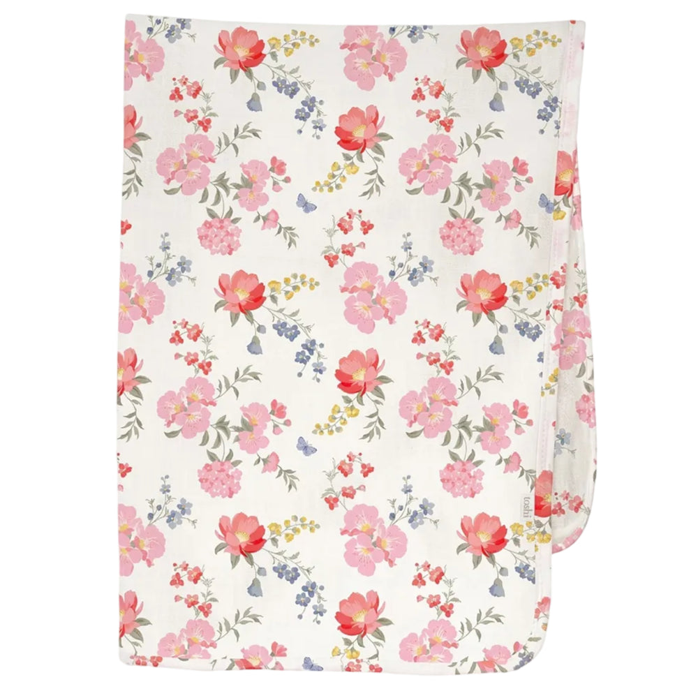 A folded baby blanket or swaddle featuring a delicate Australina floral pattern with pink, red, and blue flowers on a warm cream background, shown against a light gray studio backdrop.