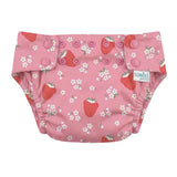 A pink reusable cloth swim nappy with a strawberry and white flower print, featuring three snap closures on the front and a visible 'toshi' brand tag.