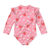 A pink long-sleeve baby bodysuit with a strawberry and white flower print, featuring ruffled shoulder details, shown flat on a light gray background.