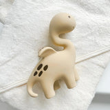 Dinosaur-shaped teething toy on a white towel with a white background
