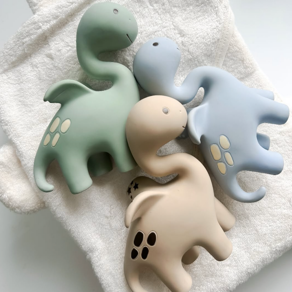 A collection of Diplo the Dino-Dragon teethers in various colors including blue, green and beige, designed for babies.