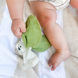 Baby holding a green cloth leaf attached to a koala teether