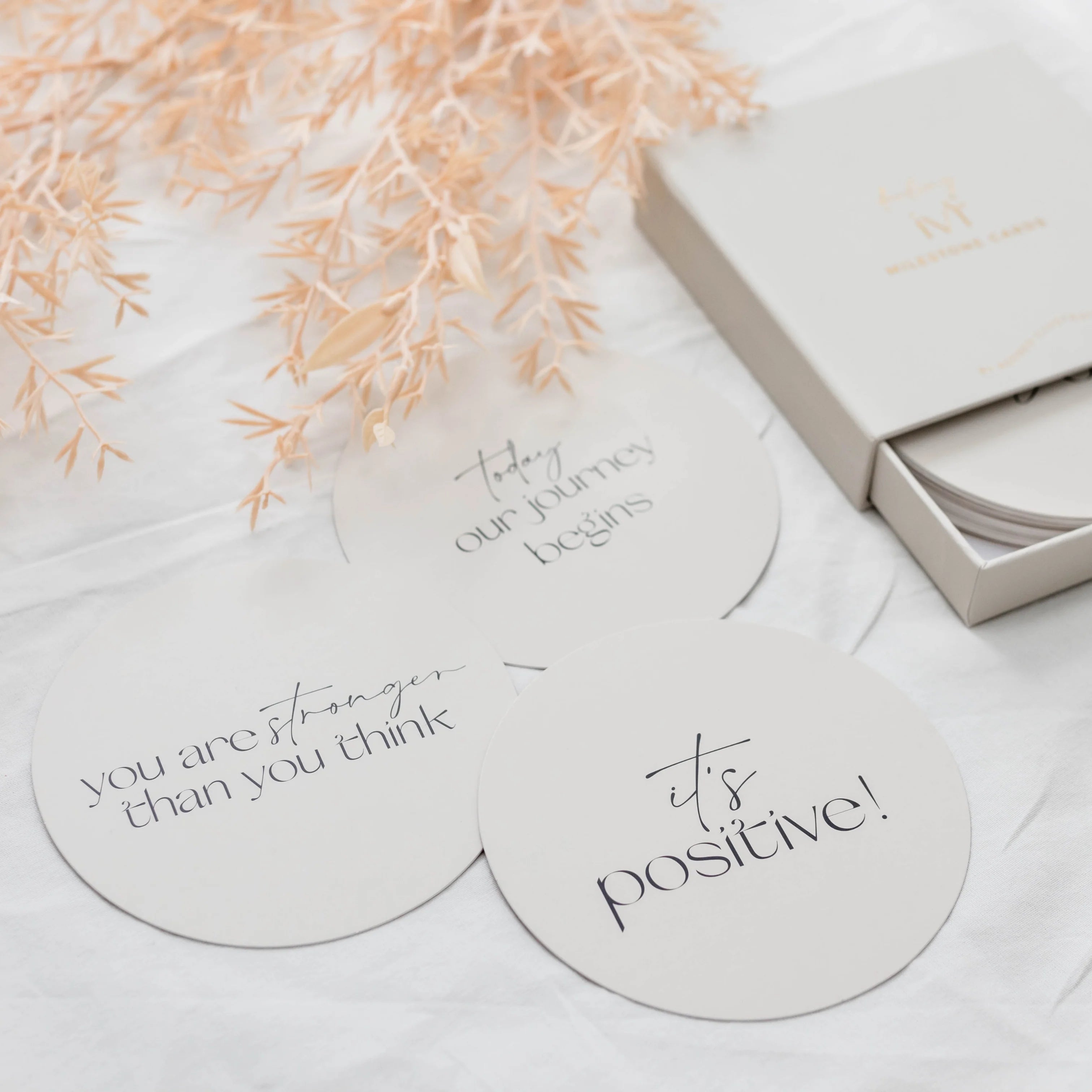 Round  plaques with motivational phrases on a light surface with decorative elements to encourage your pregnancy journey