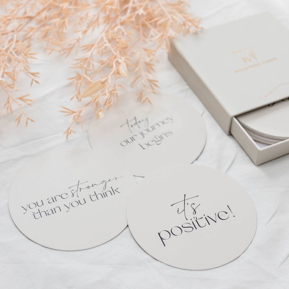 Round  plaques with motivational phrases on a light surface with decorative elements to encourage your pregnancy journey