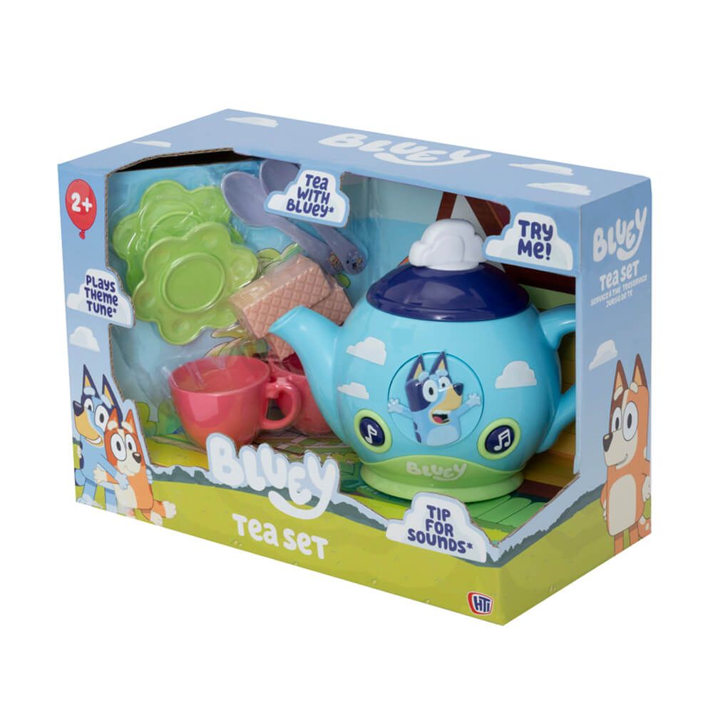 Bluey tea set in its retail packaging, featuring a light blue teapot with a dark blue lid, a pink cup, green plates, and other accessories visible through a clear plastic window.