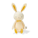 A soft plush toy in the shape of a bunny with yellow ears and a striped body, predominantly in a cream color.