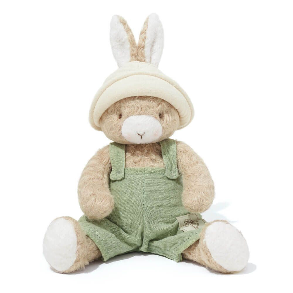 Stuffed toy rabbit wearing a beige hat and green overalls on a white background