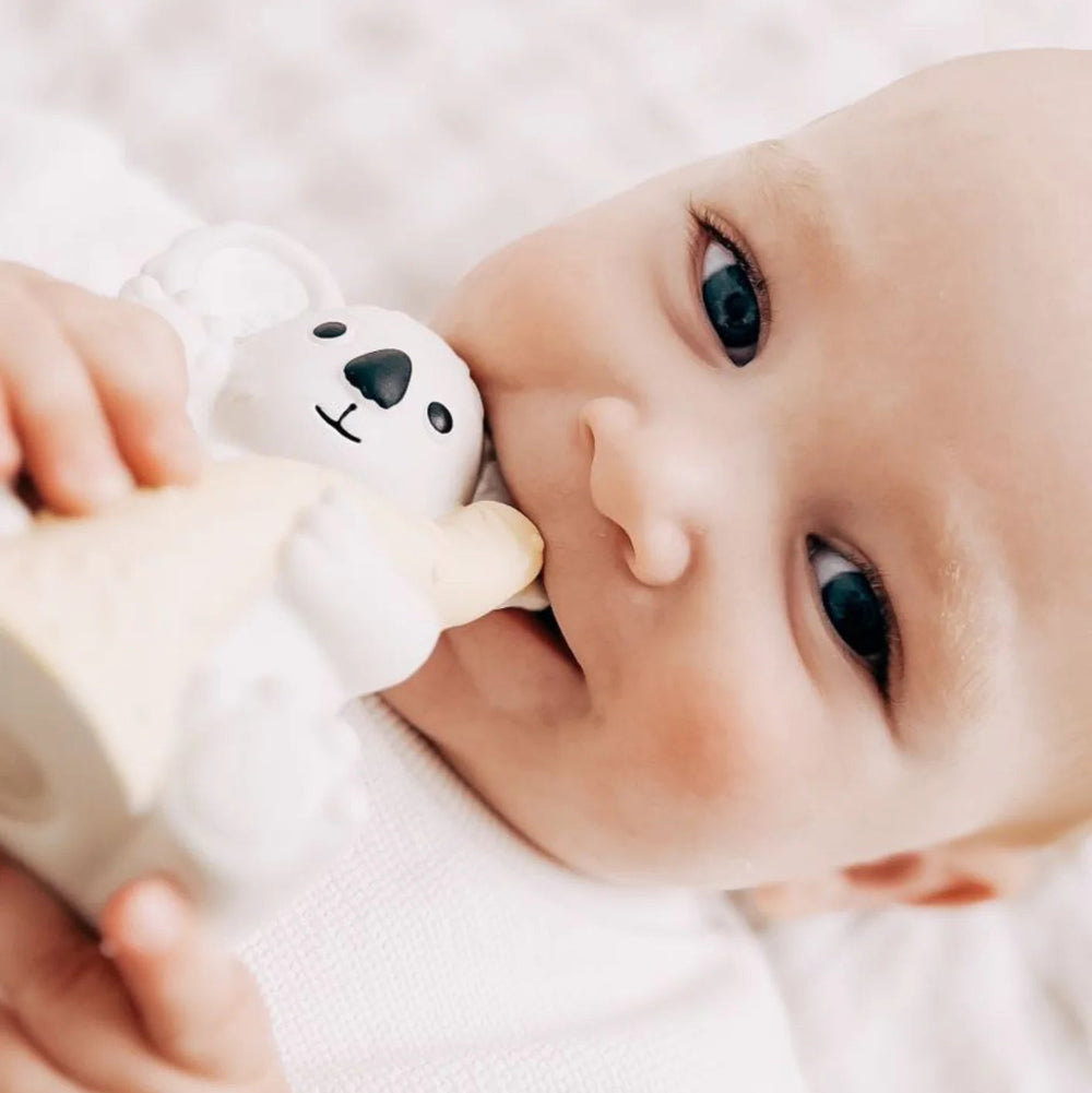Baby smiling while chewing on a koala teether 