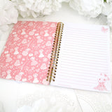 Claris book opened showing ruled pink lines with a claris image with 3 pink butterflies above her in the bottom right corner