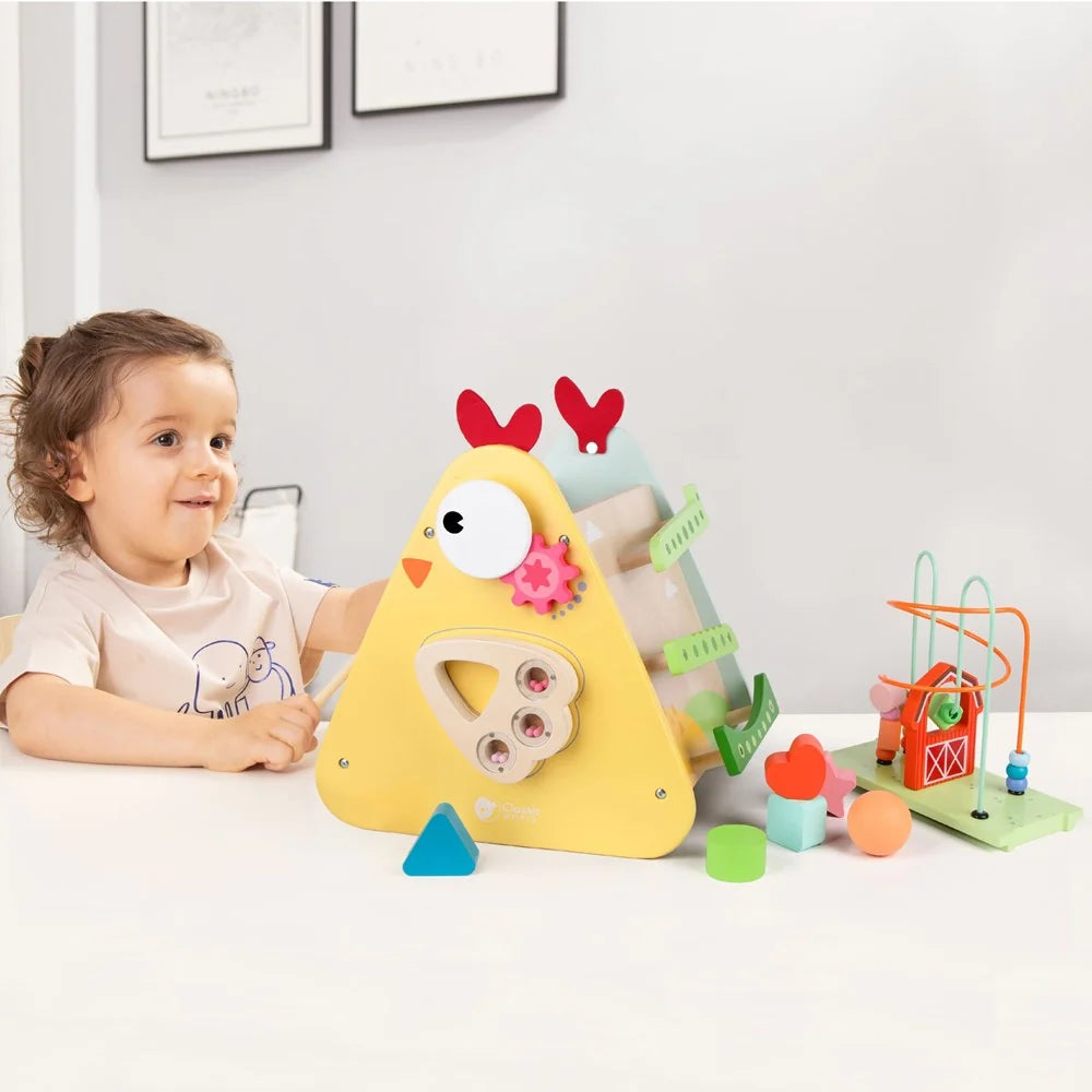 Child playing with a yellow toy chicken in a room with a white wall and framed pictures.