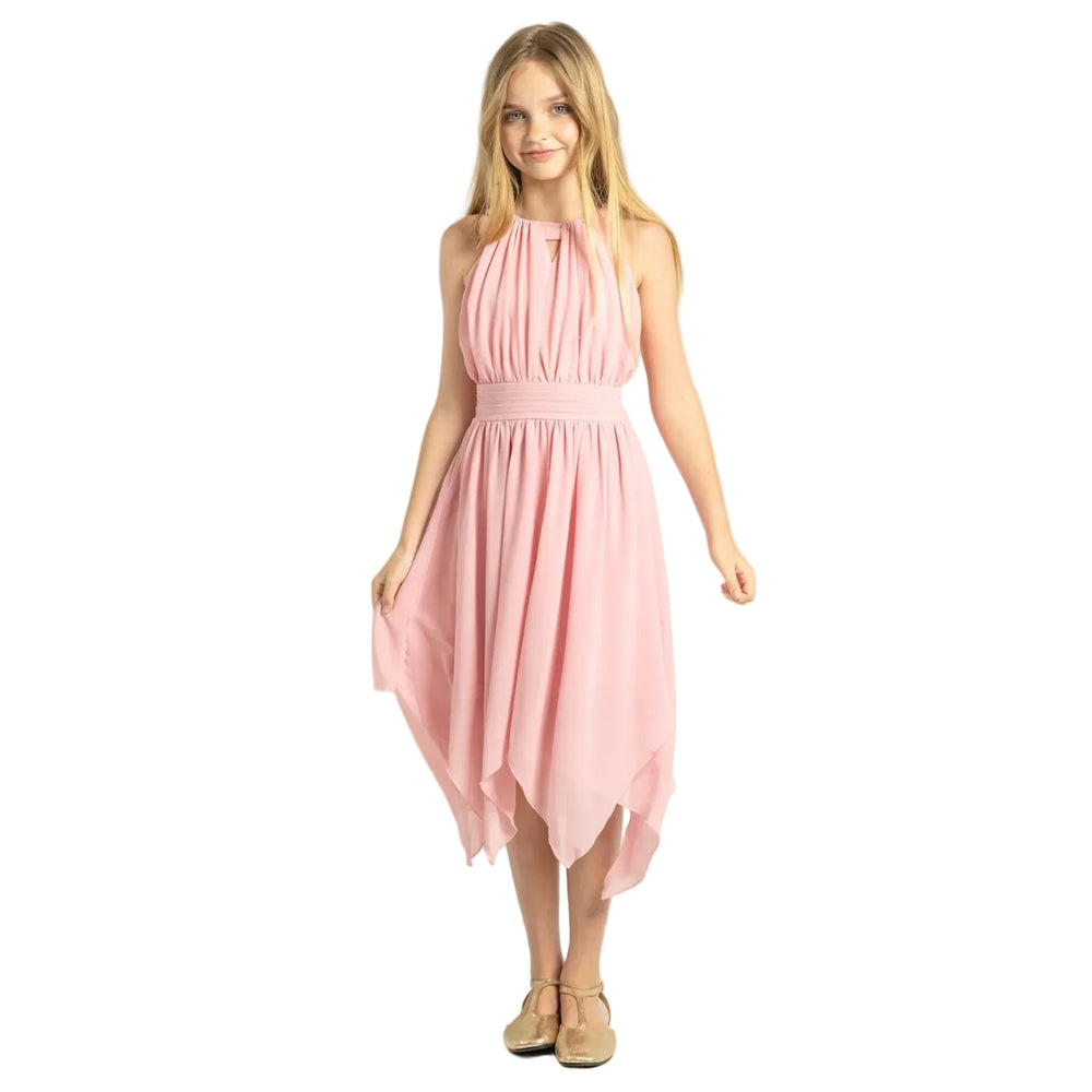 A young girl modeling a light pink sleeveless halter midi dress with a pleated bodice and flowing skirt, paired with beige flat shoes, against a solid beige studio background.