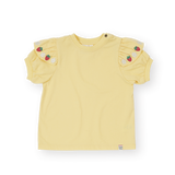 Yellow t-shirt with shoulder embellishments on a white background