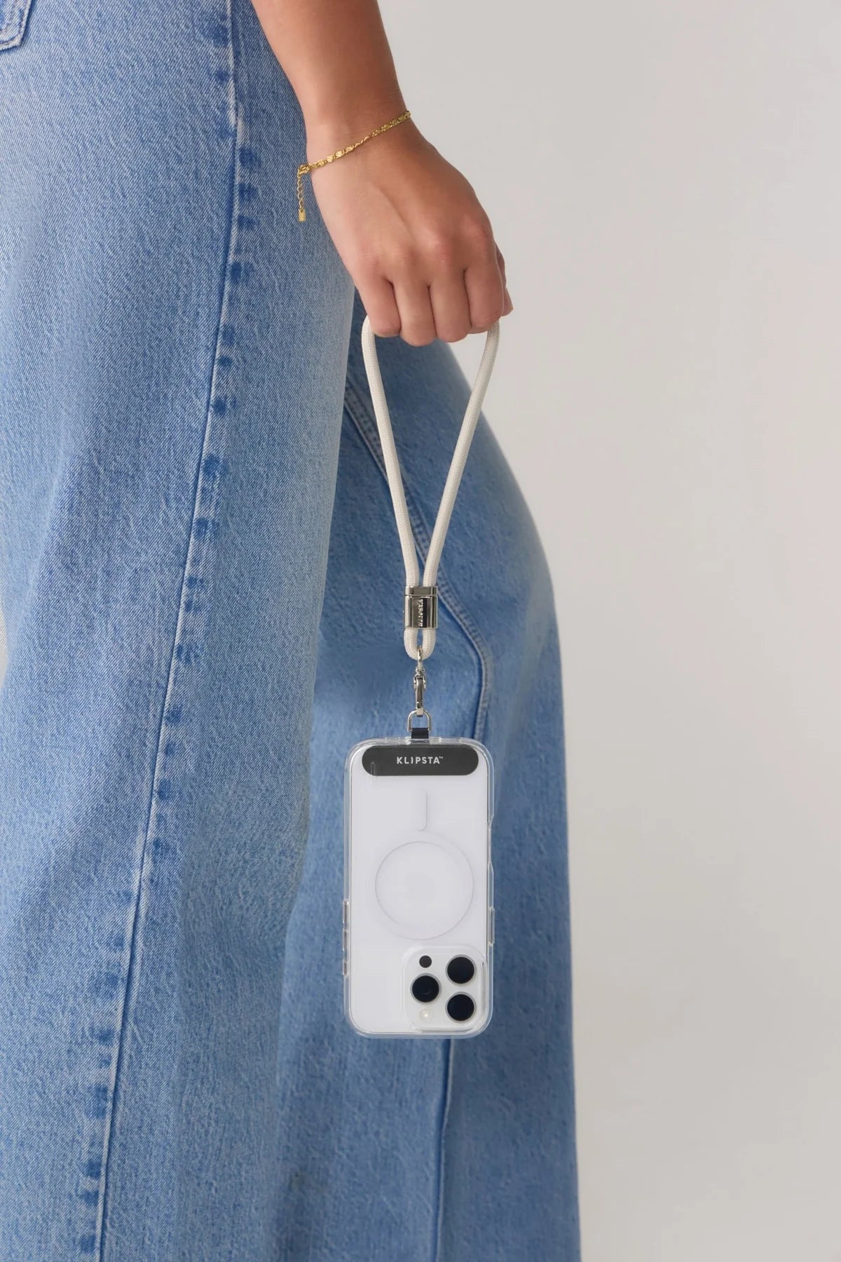 Phone case with a lanyard held by a person wearing blue jeans.