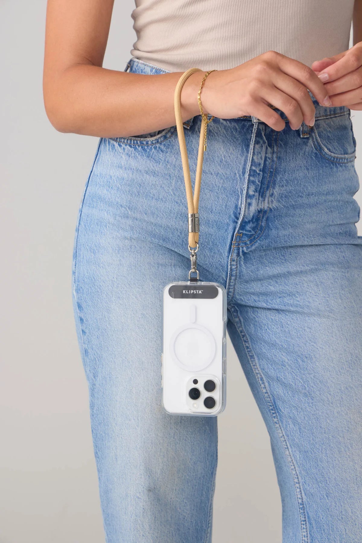 Person wearing a phone case with a lanyard on a plain background