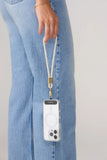 A close-up of a person wearing light blue denim jeans, holding a white phone case with a matching white wrist strap and gold hardware.