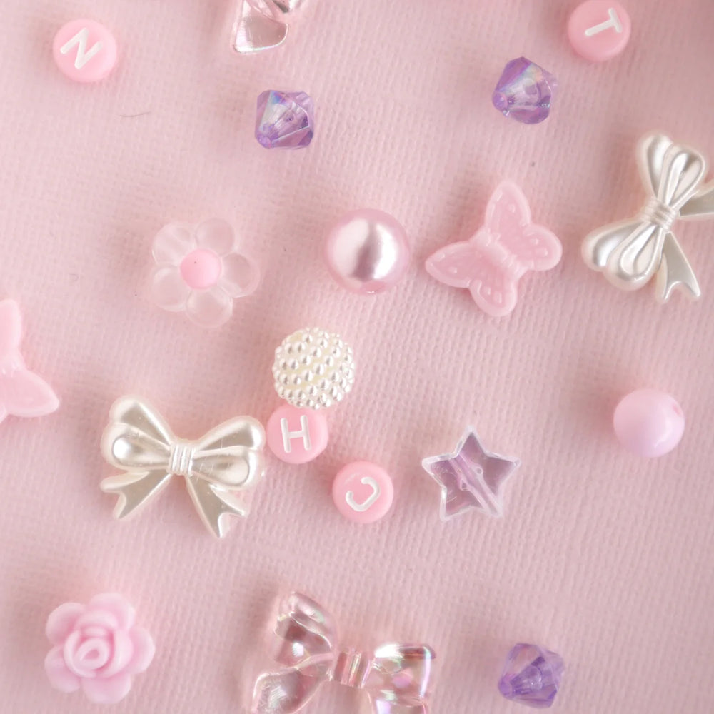 Decorative bead elements like bows, hearts, and flowers on a pink background
