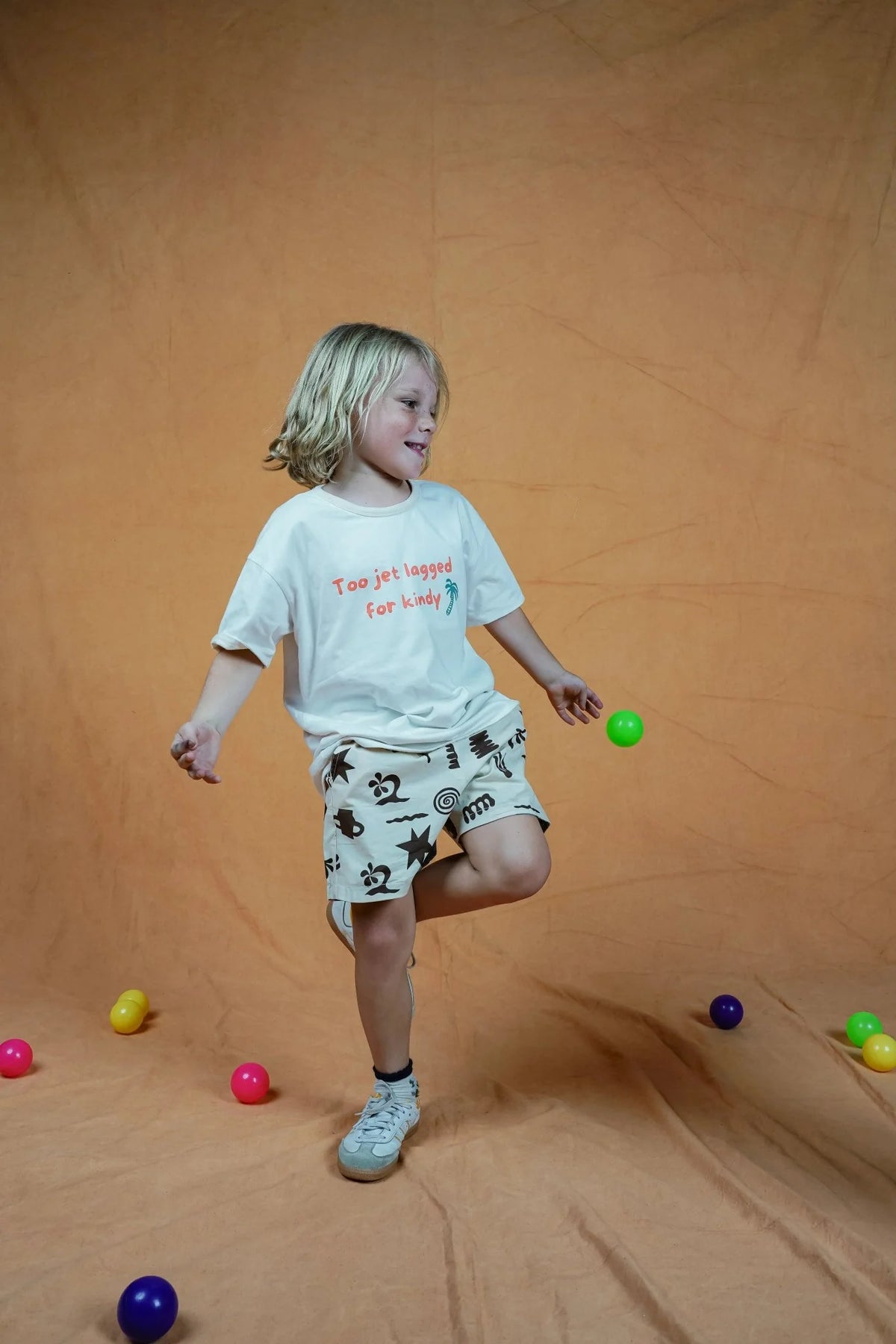 Child playing with colorful balls on a beige background