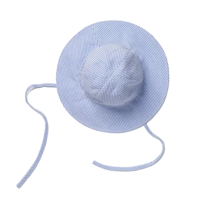 A light blue and white striped sun hat with a wide brim, a matching fabric-covered crown, and long tie straps, laid flat on a light gray background.
