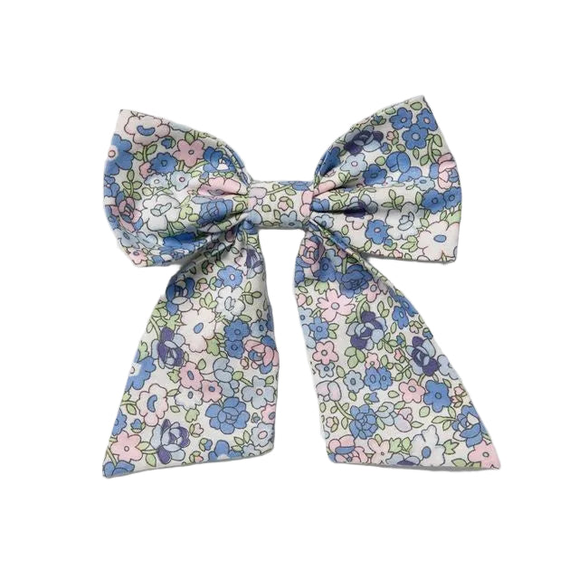 A fabric hair bow with a delicate floral print in shades of blue, pink, and green on a white background, photographed flat against a light gray backdrop.