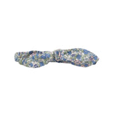 A fabric headband with a dense blue, pink, and white floral print, photographed flat against a neutral light gray background.