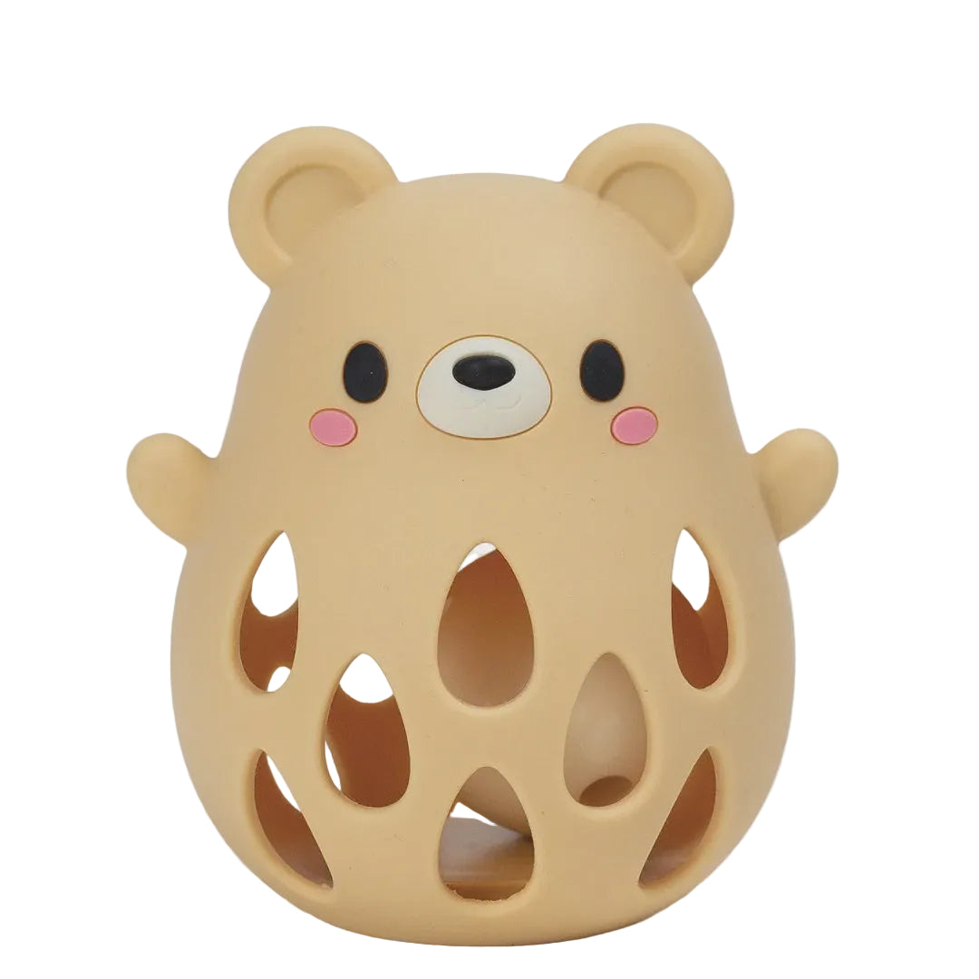 A cute bear-shaped silicone teething toy or bath mat in a warm beige/tan color, featuring a smiling face with black eyes, a white snout, pink cheeks, and cutout details on the body, shown on a plain white background.