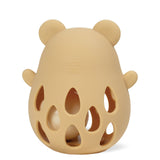 A beige silicone baby teether with a bear head silhouette, featuring ear shapes, side lugs, and cutout teardrop patterns on the front, shown on a white background.