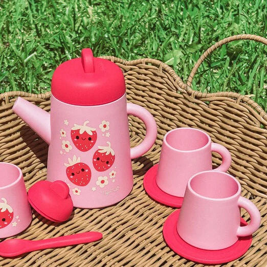 A pink silicone tea set with strawberry designs, including a teapot, cups, saucers, sugar bowl, and a spoon.
