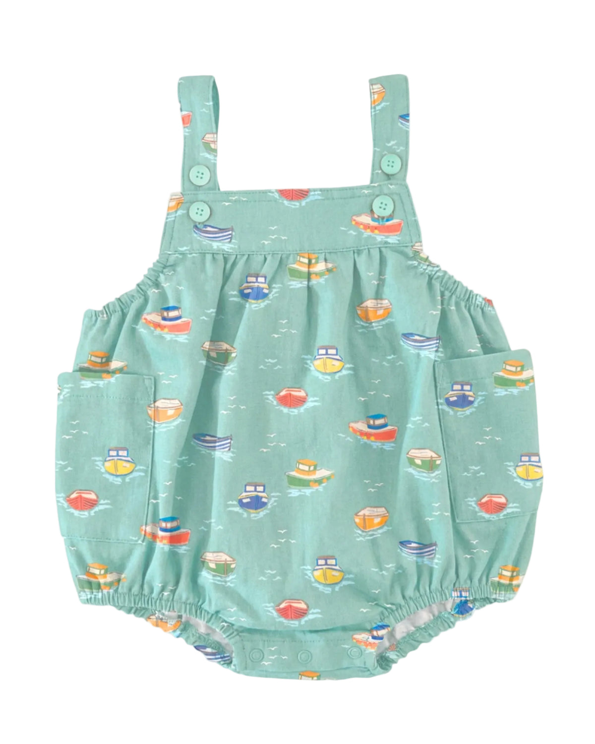A mint green baby romper with an all-over colorful tugboat print, featuring shoulder straps with decorative buttons and side pockets, shown against a light gray background.