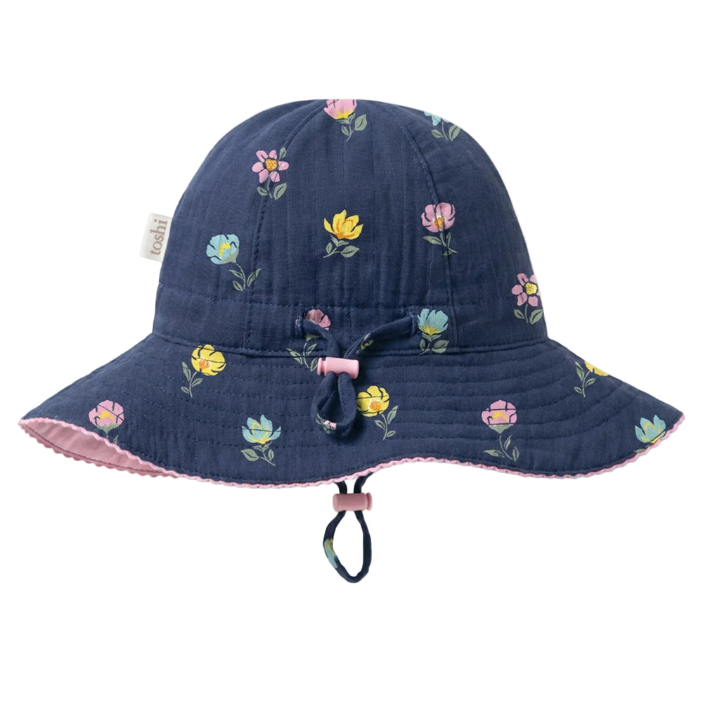 A navy blue quilted bucket hat with a colorful floral print, featuring a pink chin strap and a small fabric brand tag on the side.