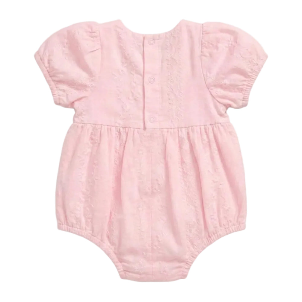 A light pink baby romper with short puff sleeves, a buttoned back, and a gathered waist, shown against a plain light gray background.