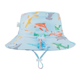 A blue and white baby sunhat with a shark pattern, featuring a head tie and chin strap for adjustable fitting, labeled with 'UPF50+' for sun safety.