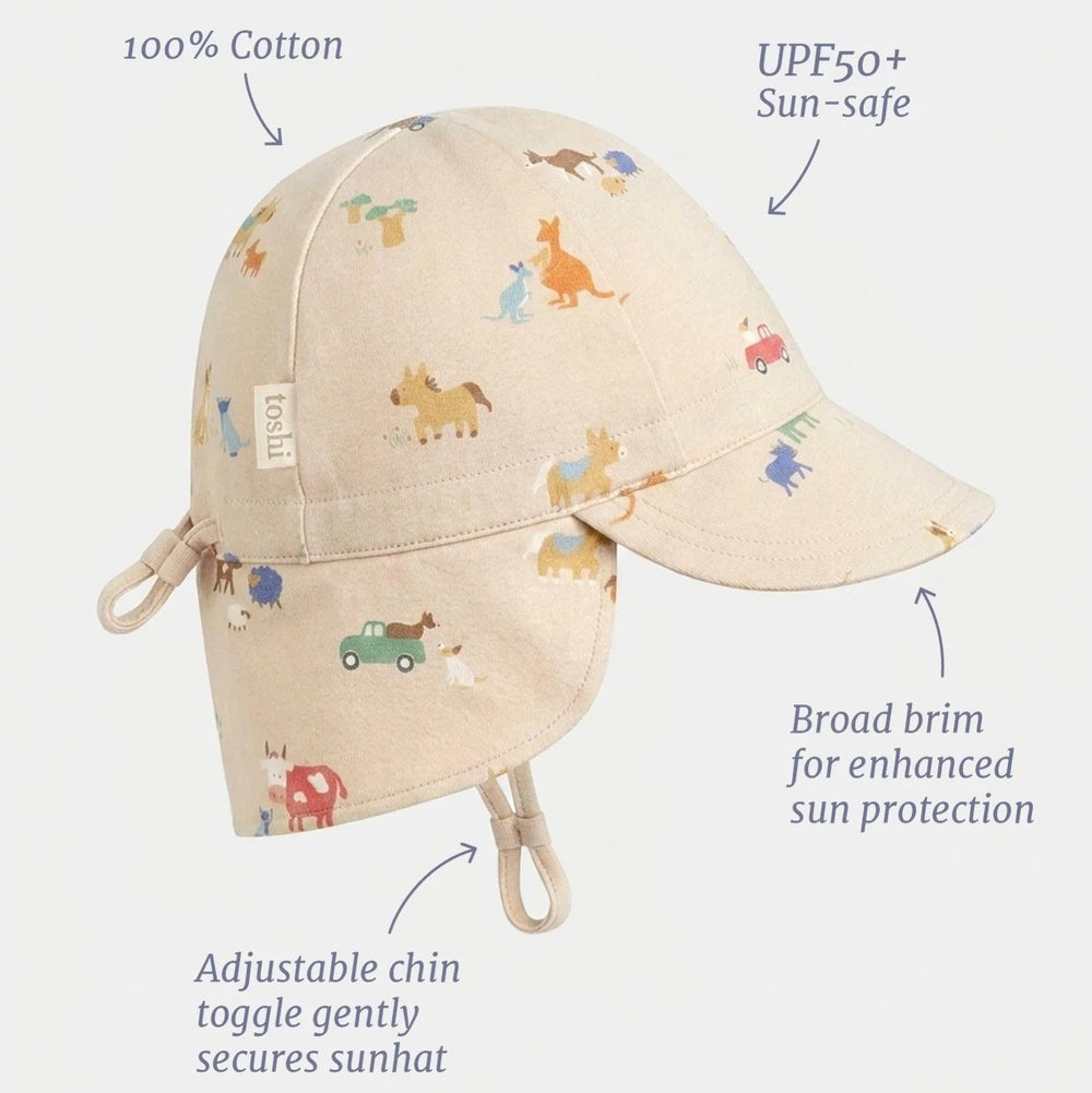 A baby sun hat with a neck flap and chin strap, shown on a light gray background with text callouts highlighting features like '100% Cotton', 'UPF50+ Sun-safe', 'Broad brim for enhanced sun protection', and 'Adjustable chin toggle gently secures sunhat'. The hat is beige with a colorful animal print.