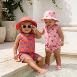 Toshi design swim outfits of a boy and a girl wearing swim vests and matching bottoms of swim boardies and swim nappy with also matching hats