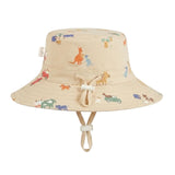 A beige bucket hat with an all-over colorful aussie and farm animal print, featuring a matching beige chin strap and a small front tie detail, shown against a plain light gray background.
