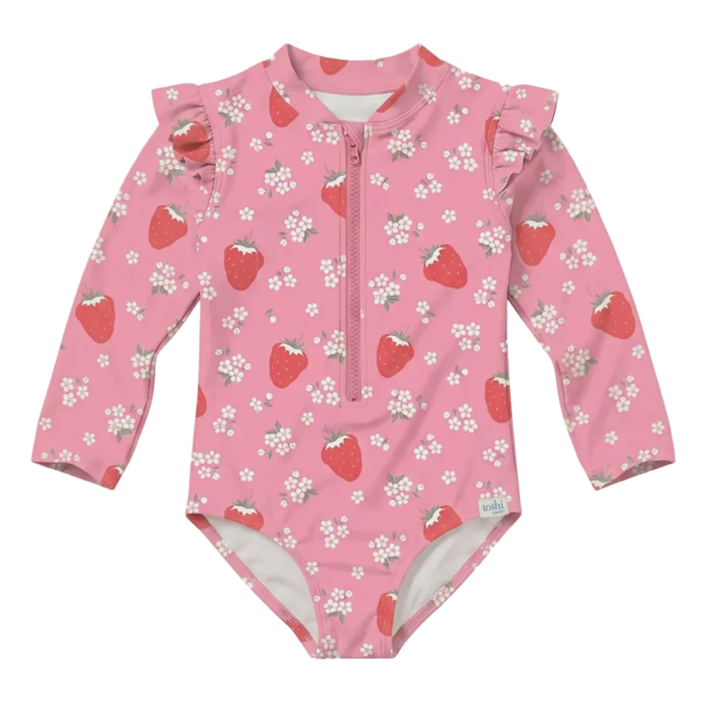 A pink long-sleeve baby swimsuit with a front zipper, ruffled shoulder details, and an all-over strawberry and white flower print, shown against a solid light gray background.