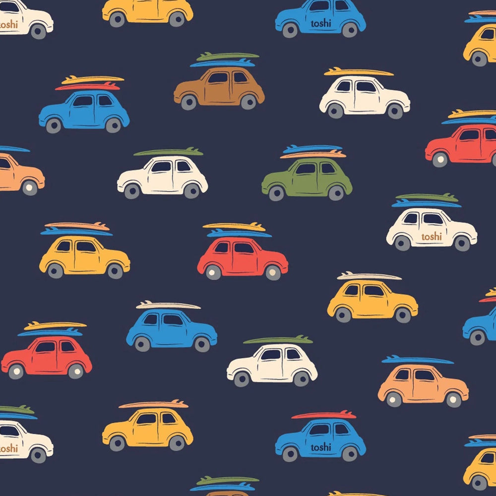 A repeating pattern of small retro cars in yellow, blue, red, orange, green, and cream, each carrying surfboards, on a dark navy background. Some cars have the word 'tobi' printed on them.