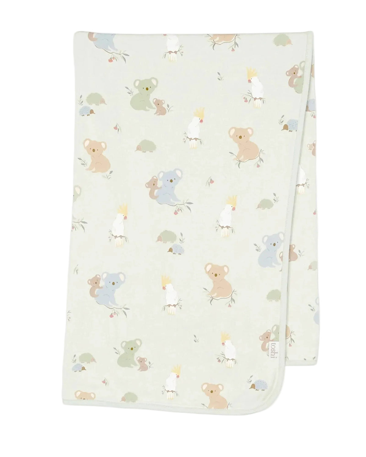 A folded knit baby blanket with a light sage green background and a playful pattern of cartoon koalas, kangaroo babies, and birds in soft pastel colors, shown on a neutral light gray background.