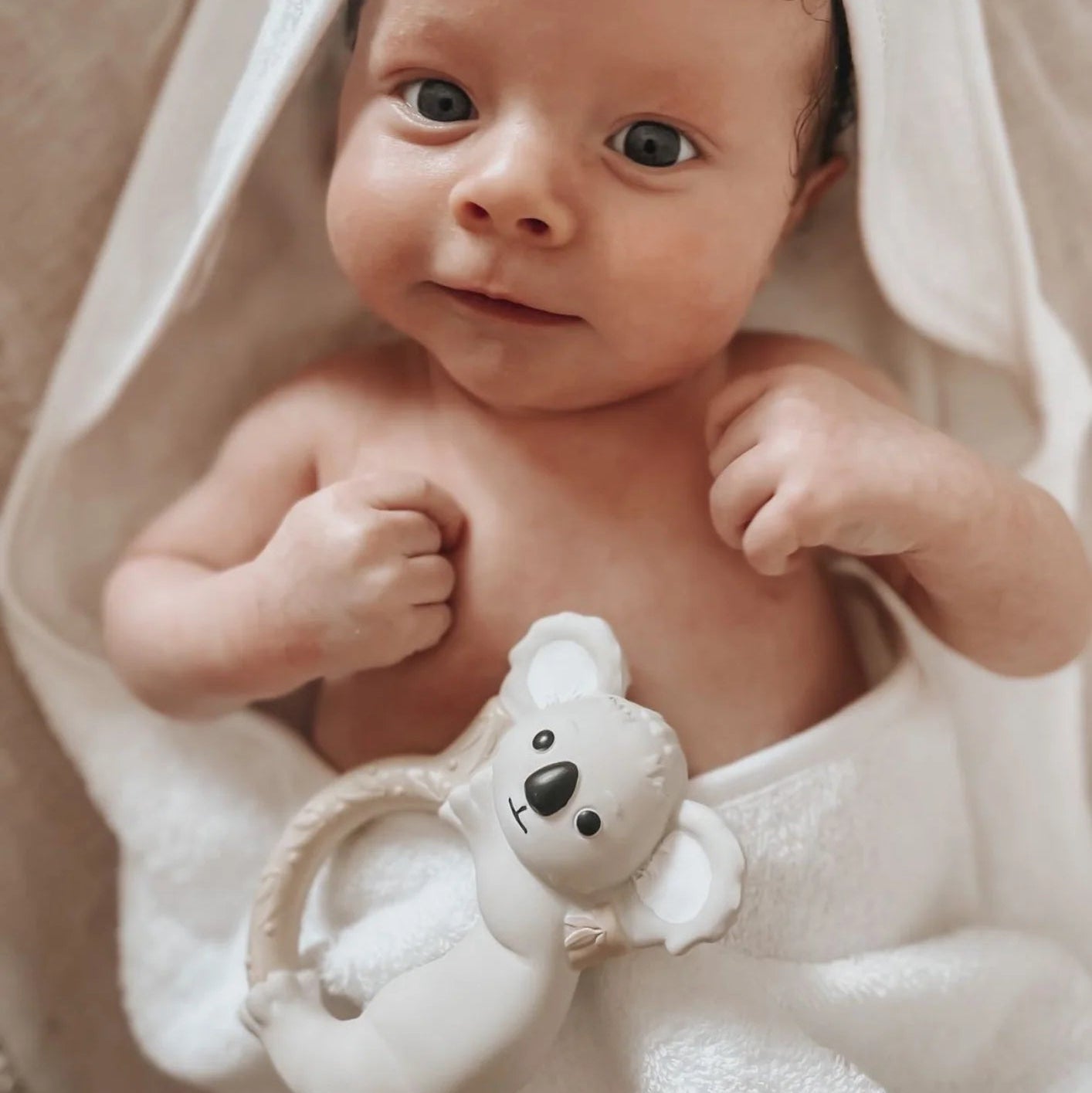 Baby wrapped in a towel and a koala ring teether on the towel