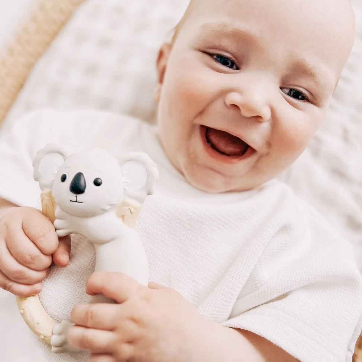 Baby smiling and holding a koala ring teether