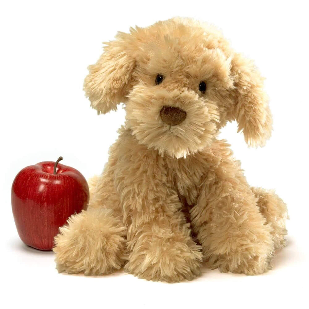 Plush dog toy next to a red apple on a white background